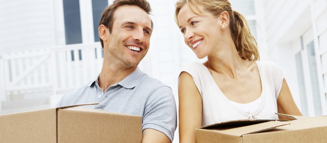 Happy mature man and woman with boxes moving in new house