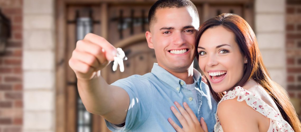 Young Military Couple In Front of Front Door of New House Holding Keys.